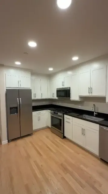 A completed white kitchen with dark countertops and a clean finished-cabinet presentation.