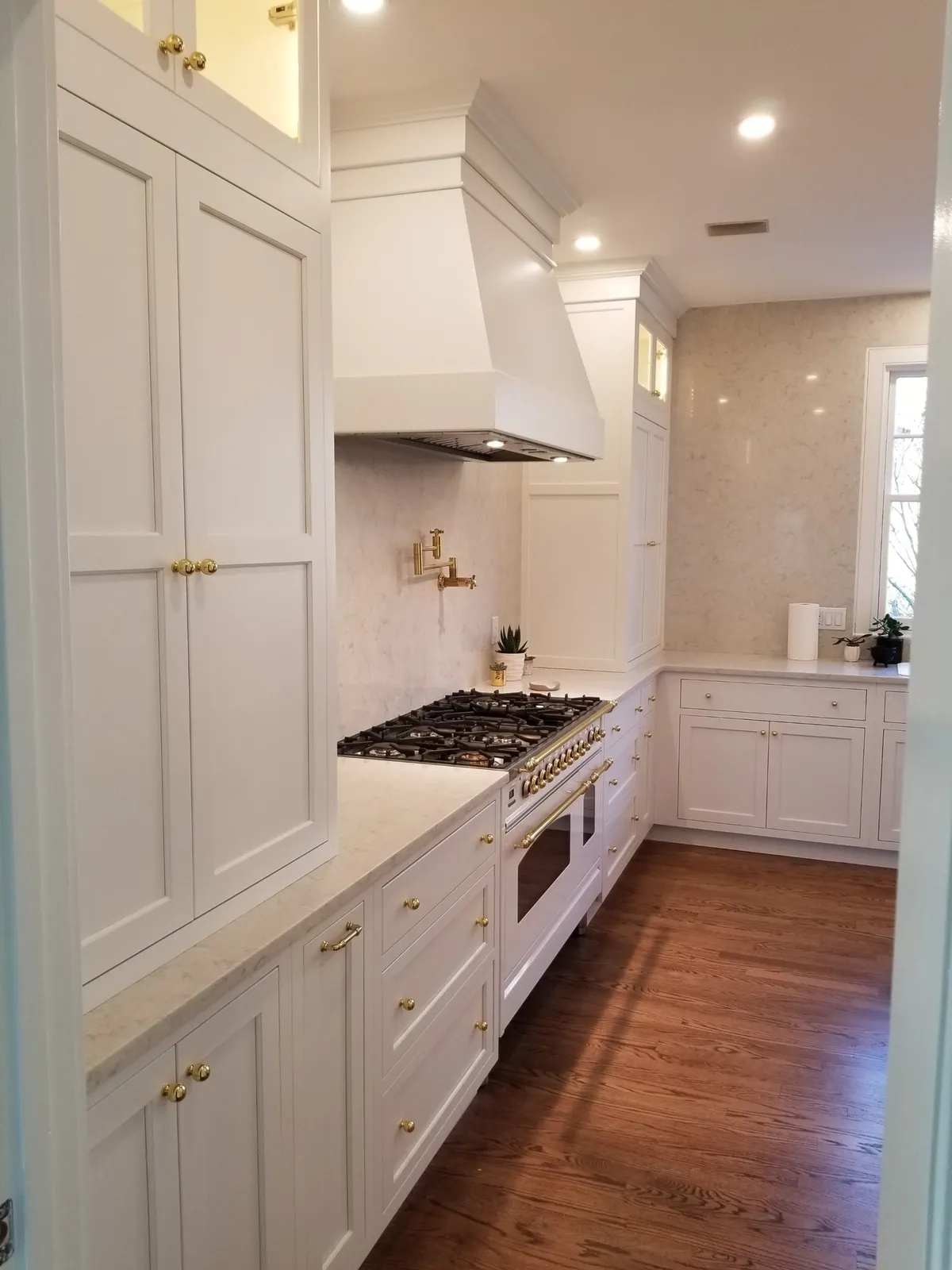 White kitchen with custom hood surround and gas range