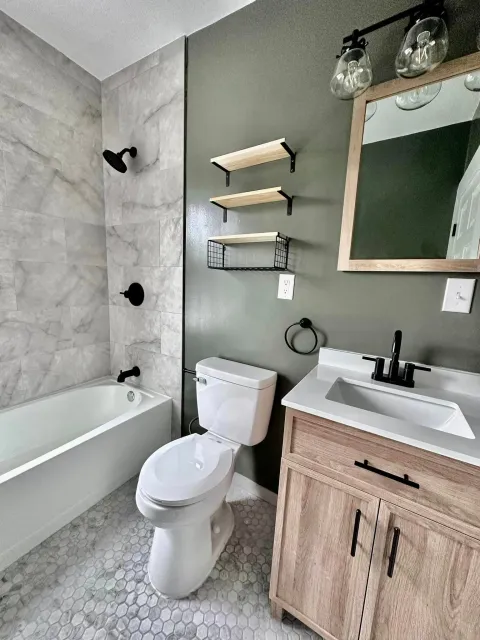a bathroom with a toilet , sink , bathtub and mirror .