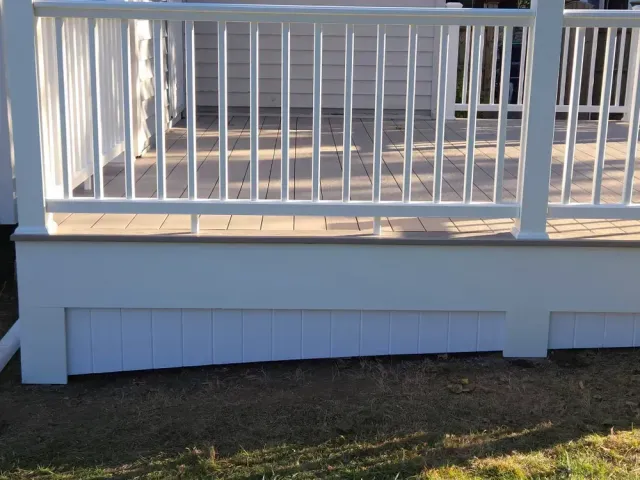 White porch railing above a light blue skirting wall over a grassy yard