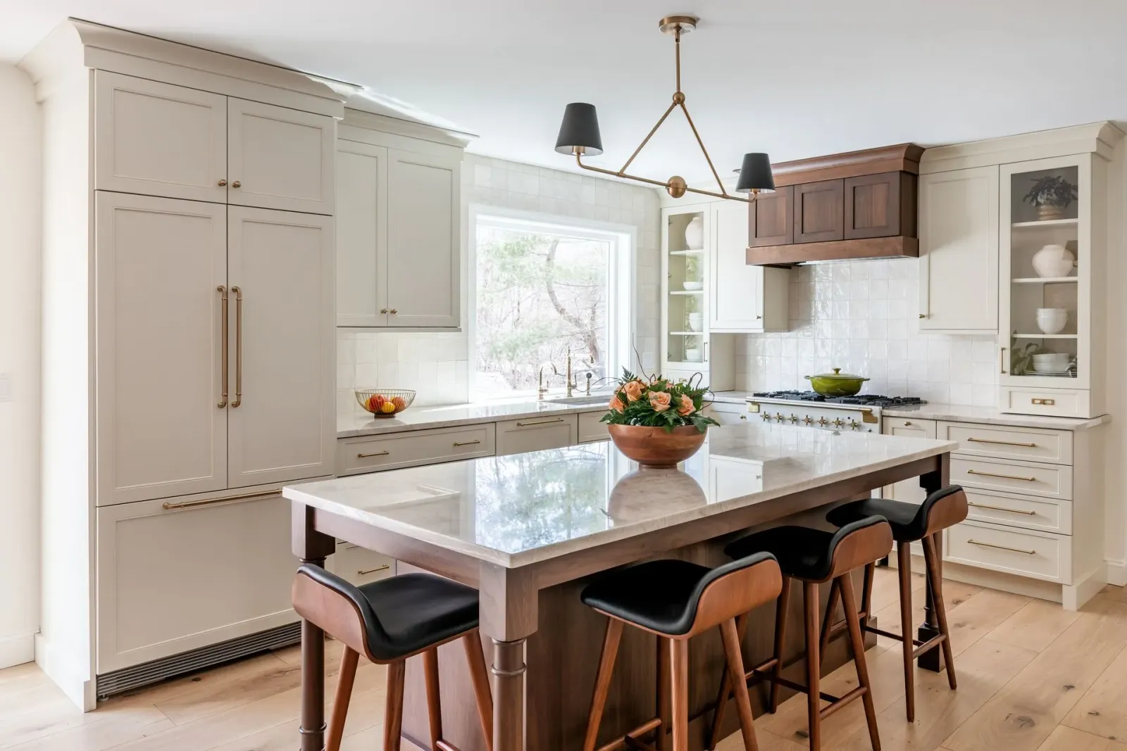 Bright modern kitchen with large island, white cabinets, and bar stools by a window