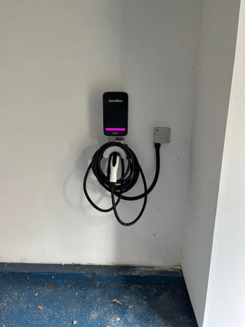 A electric car charger is hanging on a wall in a room.