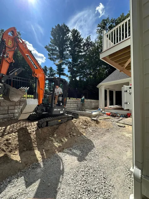 Excavator setting stone for a retaining wall on a Massachusetts property