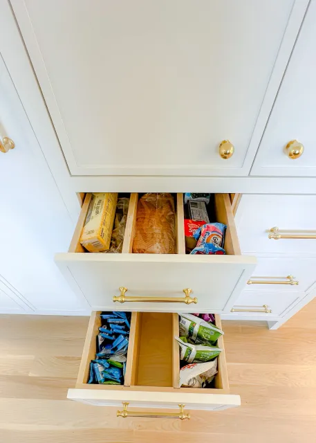 Open kitchen drawers containing snacks and bread.