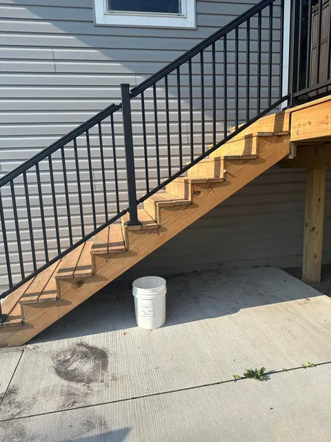 New wooden porch stairs with black metal railing