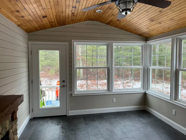 A room with a lot of windows and a ceiling fan.
