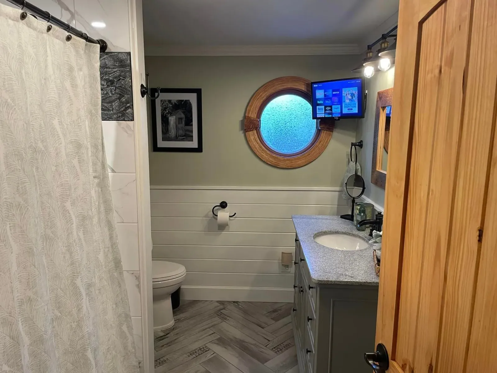 a bathroom with a sink, toilet, and television