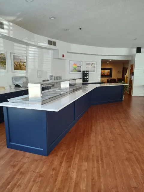 A long, navy blue counter with a food service area in a brightly lit room with wood flooring.