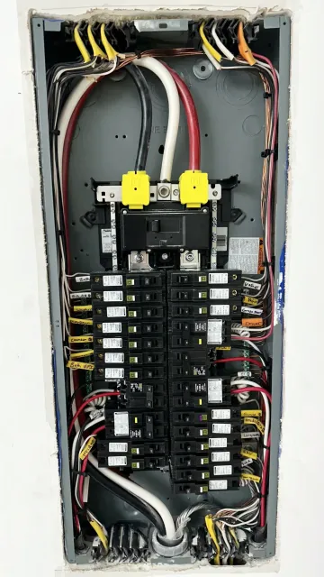 Open electrical panel with circuit breakers, labeled wires, and electrical components.