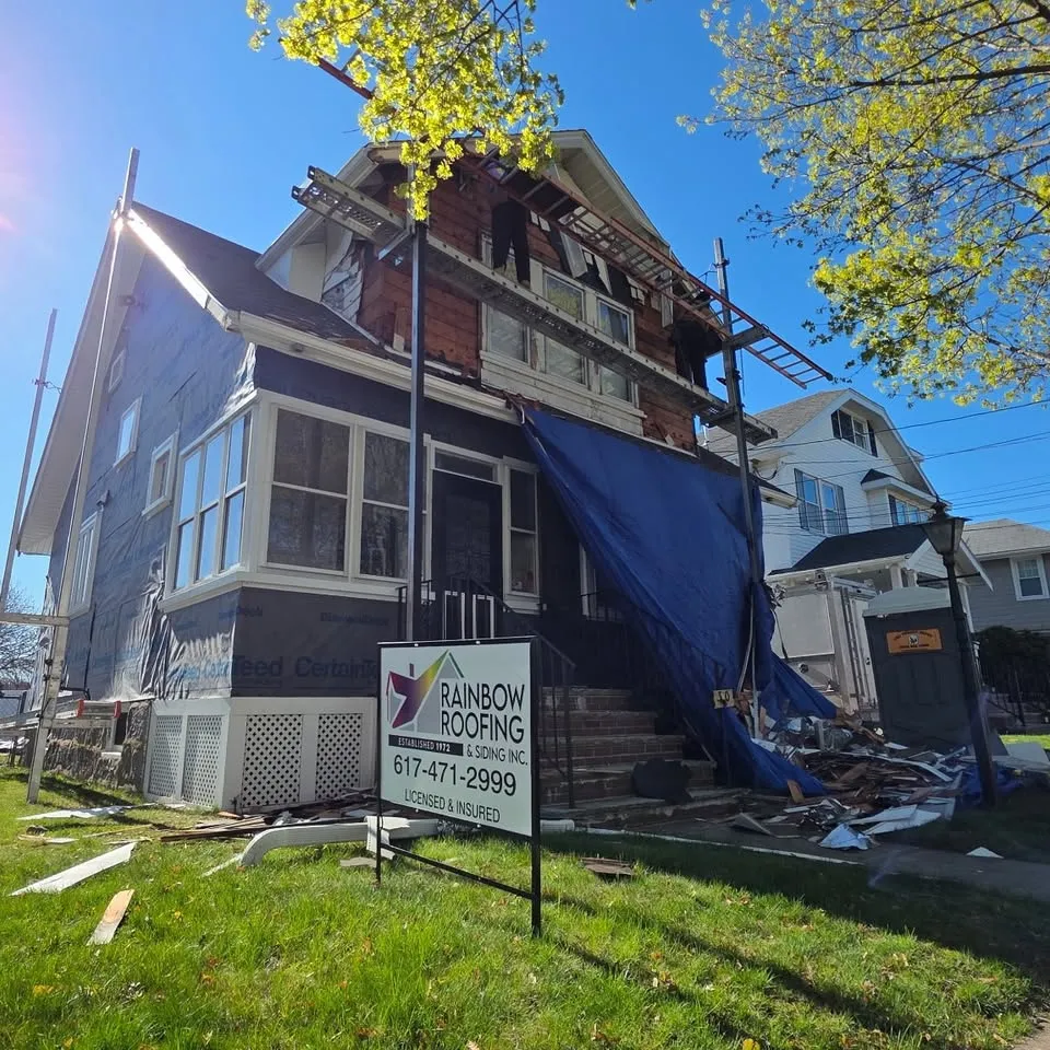 House mid-side with Rainbow Roofing & Siding job sign out front