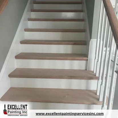 A staircase with wooden steps and white railing by excellent painting inc.