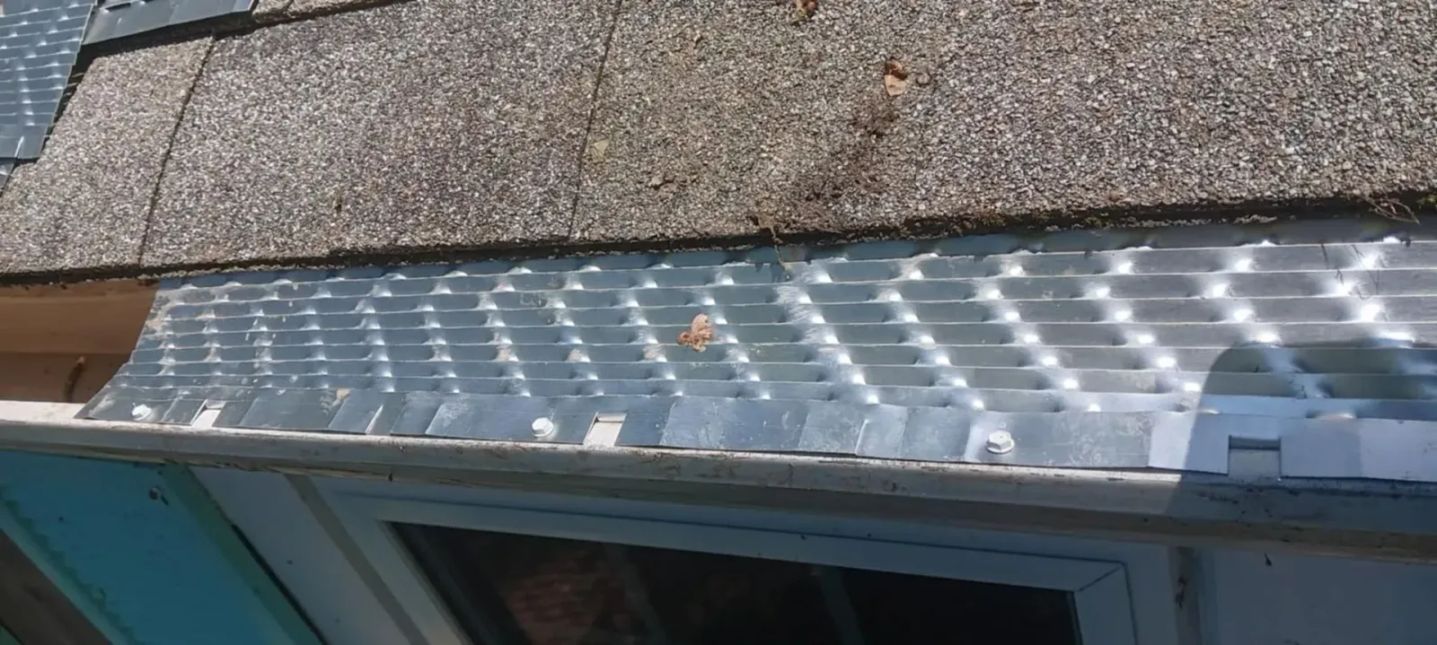 Clear plastic roof panel above a window with sunlight reflecting on it
