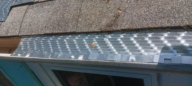 Clear plastic roof panel above a window with sunlight reflecting on it