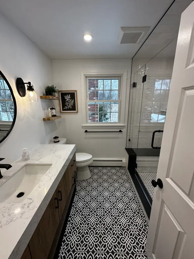 Black and white patterned bathroom floor tile installation in Hingham, MA, with glass shower and modern vanity.
