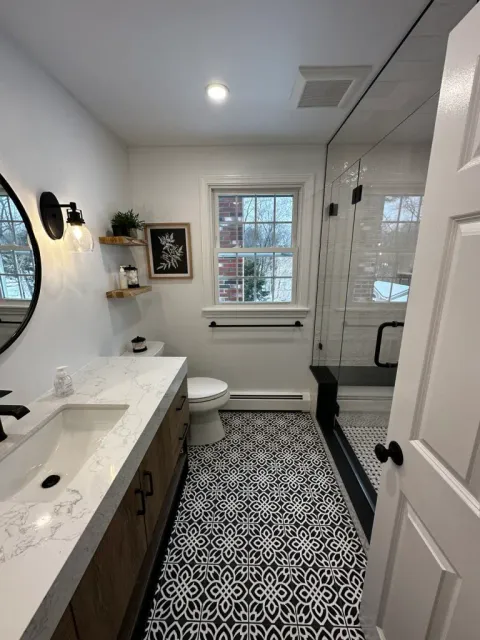 Black and white patterned bathroom floor tile installation in Hingham, MA, with glass shower and modern vanity.