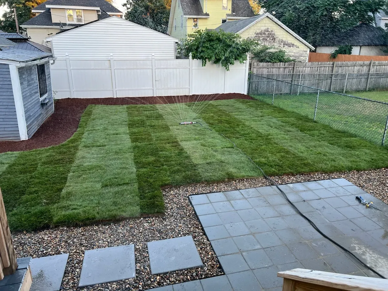Kingscapes lawn renovation with gray pavers and gravel-bordered stepping stones
