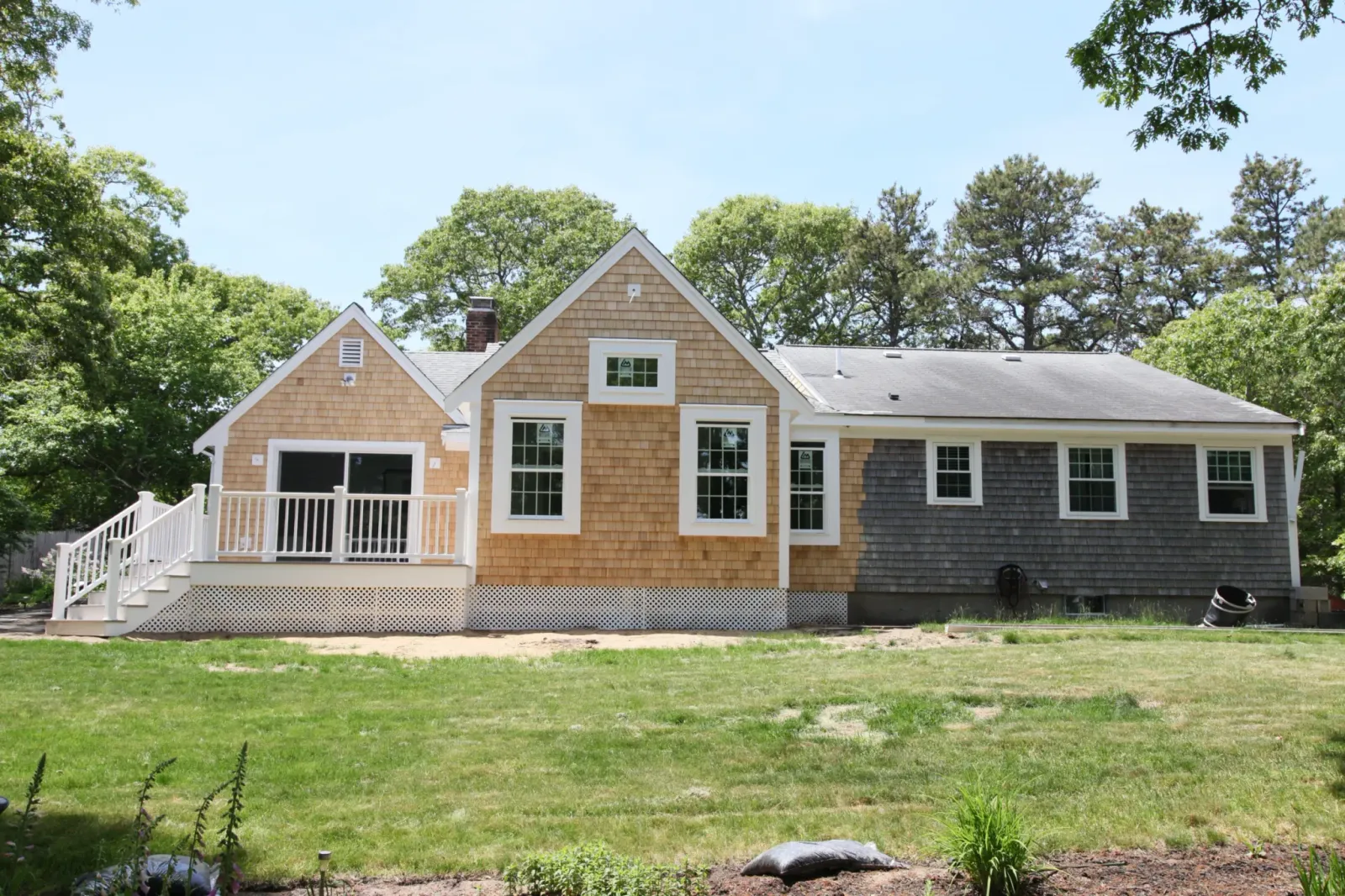 Cedar-shingled Cape Cod home with white trim, dormers and a covered front entry