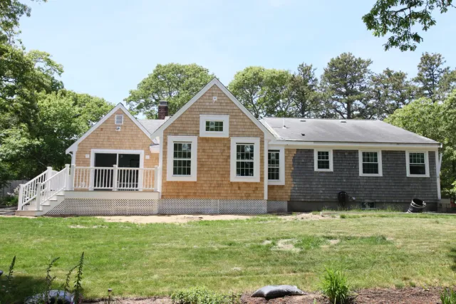 Cedar-shingled Cape Cod home with white trim, dormers and a covered front entry