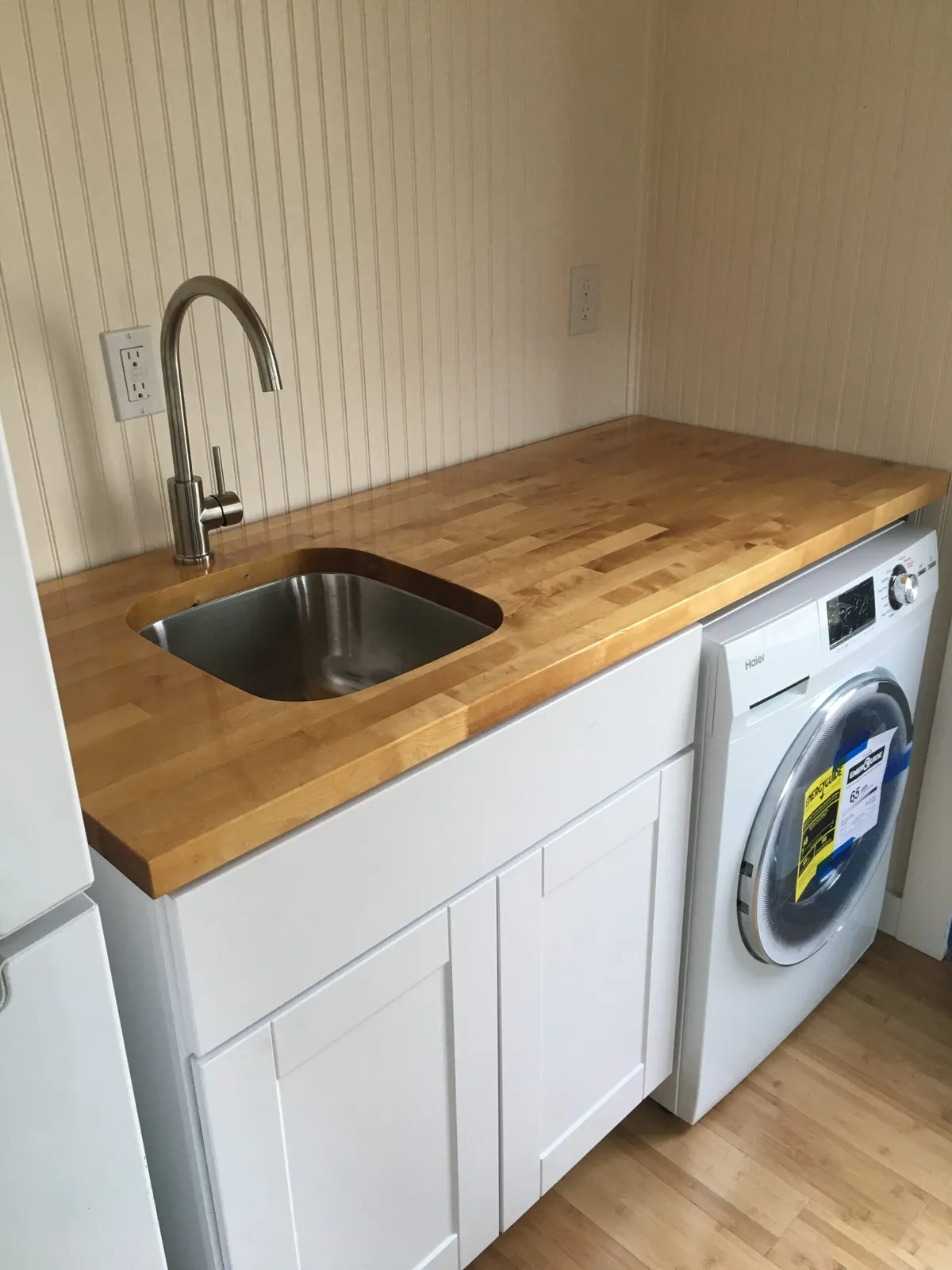 butcherblock countertop with undermount sink and faucet, cabinet, and clothes washer/dryer in a tiny house.