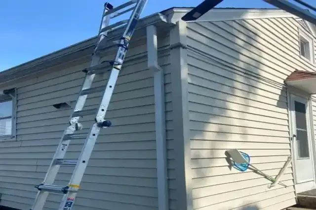 Ladder positioned against a house's exterior for siding repair, showcasing the siding's texture and color, relevant to N.E. Building & Restoration's siding installation services.