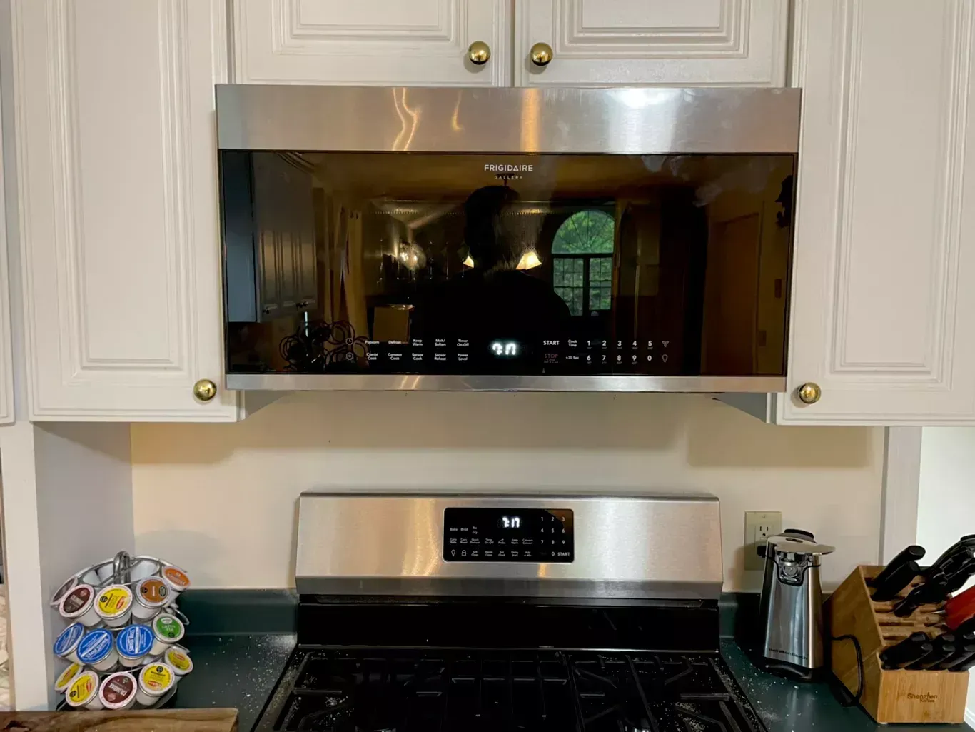 Kitchen with white cabinets, stainless steel microwave and stove, and small decor on the countertop.