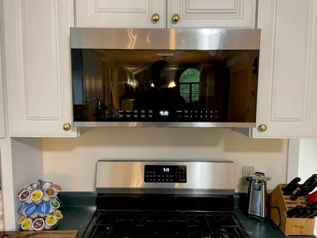 Kitchen with white cabinets, stainless steel microwave and stove, and small decor on the countertop.