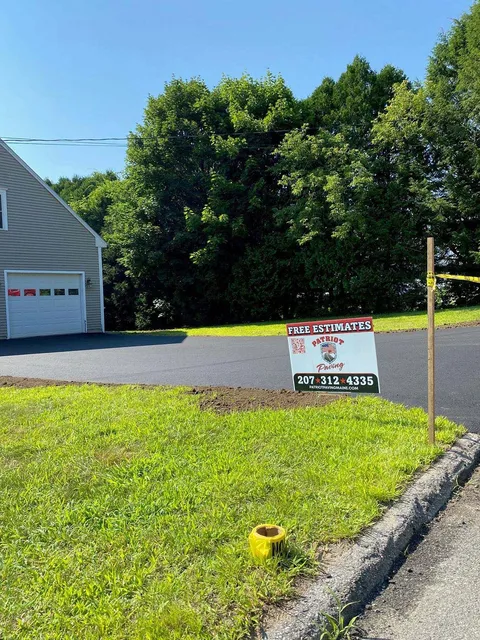 A sign is sitting in the grass in front of a house