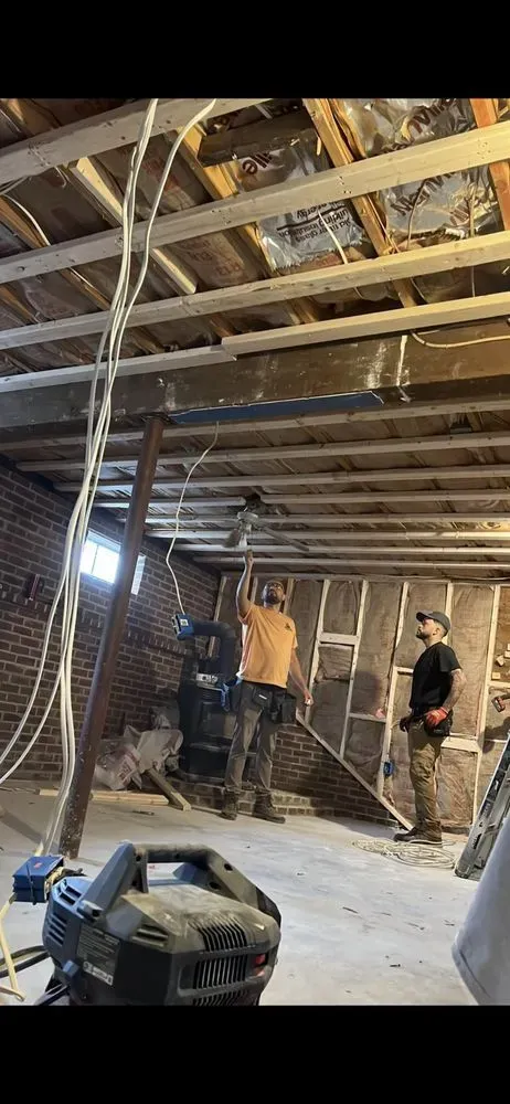 Construction workers in an unfinished room, working on the ceiling.