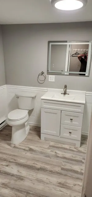 A bathroom with a toilet , sink and mirror.