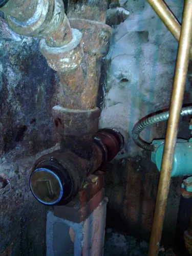 Corroded cast-iron waste line and valve before replacement