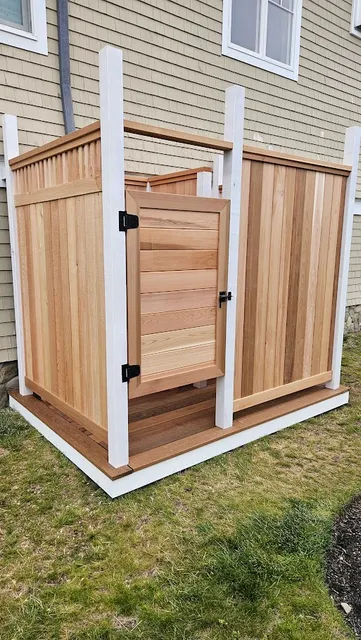 Clear cedar outdoor shower with white post trim and an ipe deck floor beside a shingled Charlestown, Rhode Island home by Toensing Construction