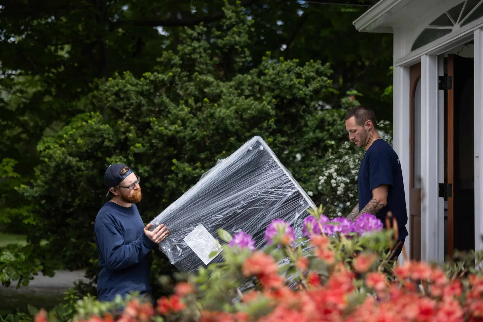 Two men unloading a large piece of furniture from a moving truck.