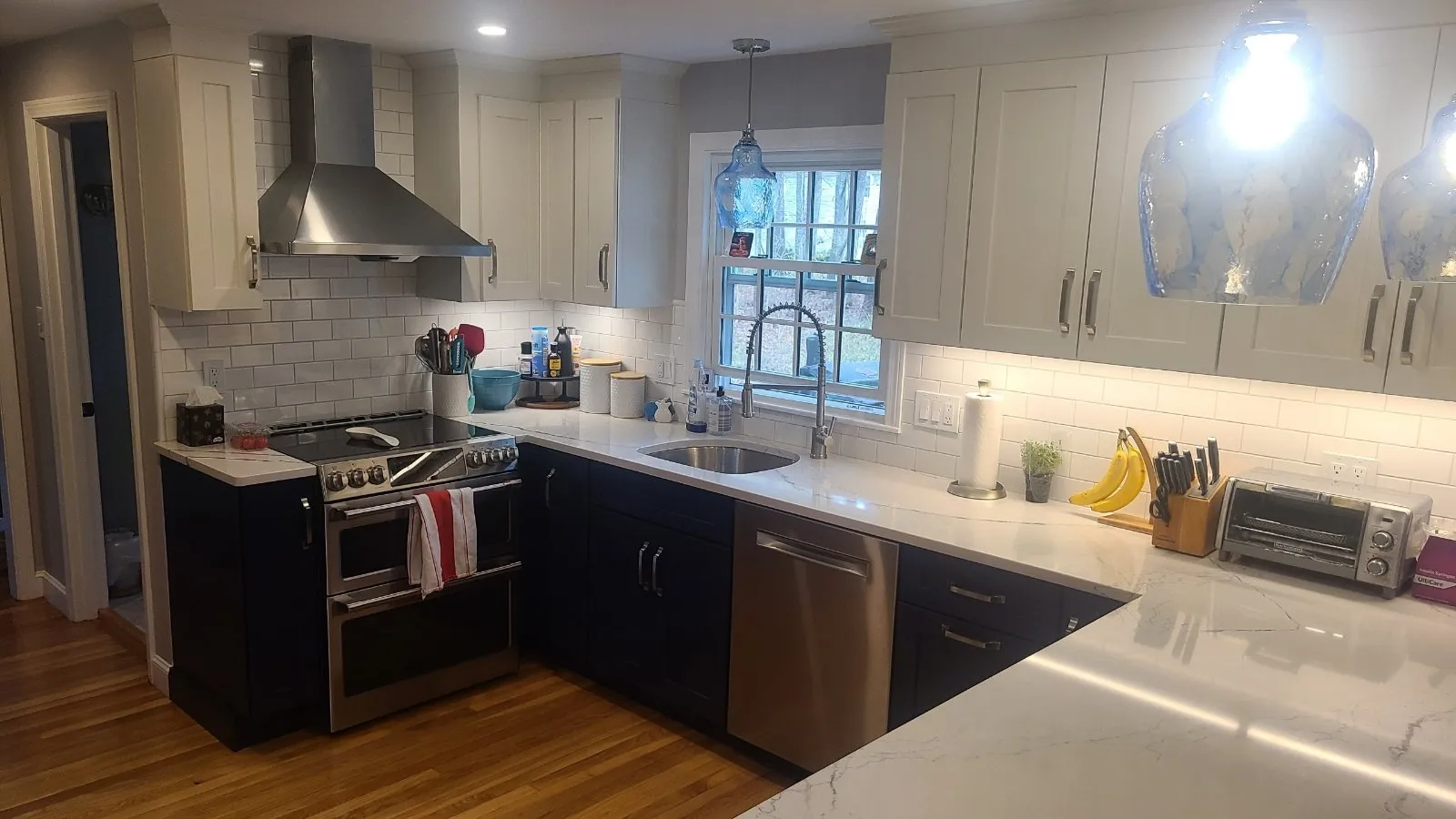 Completed kitchen with chimney hood and two-tone cabinetry
