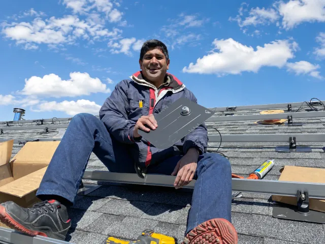 Navneet Jain and team installing solar panels on a rooftop at sunset
