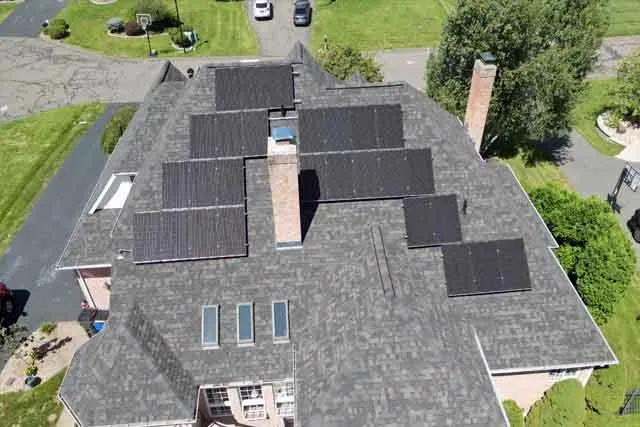 Aerial view of a residential roof featuring multiple solar panels, showcasing N.E. Building & Restoration's commitment to sustainable energy solutions and expert solar panel installation.