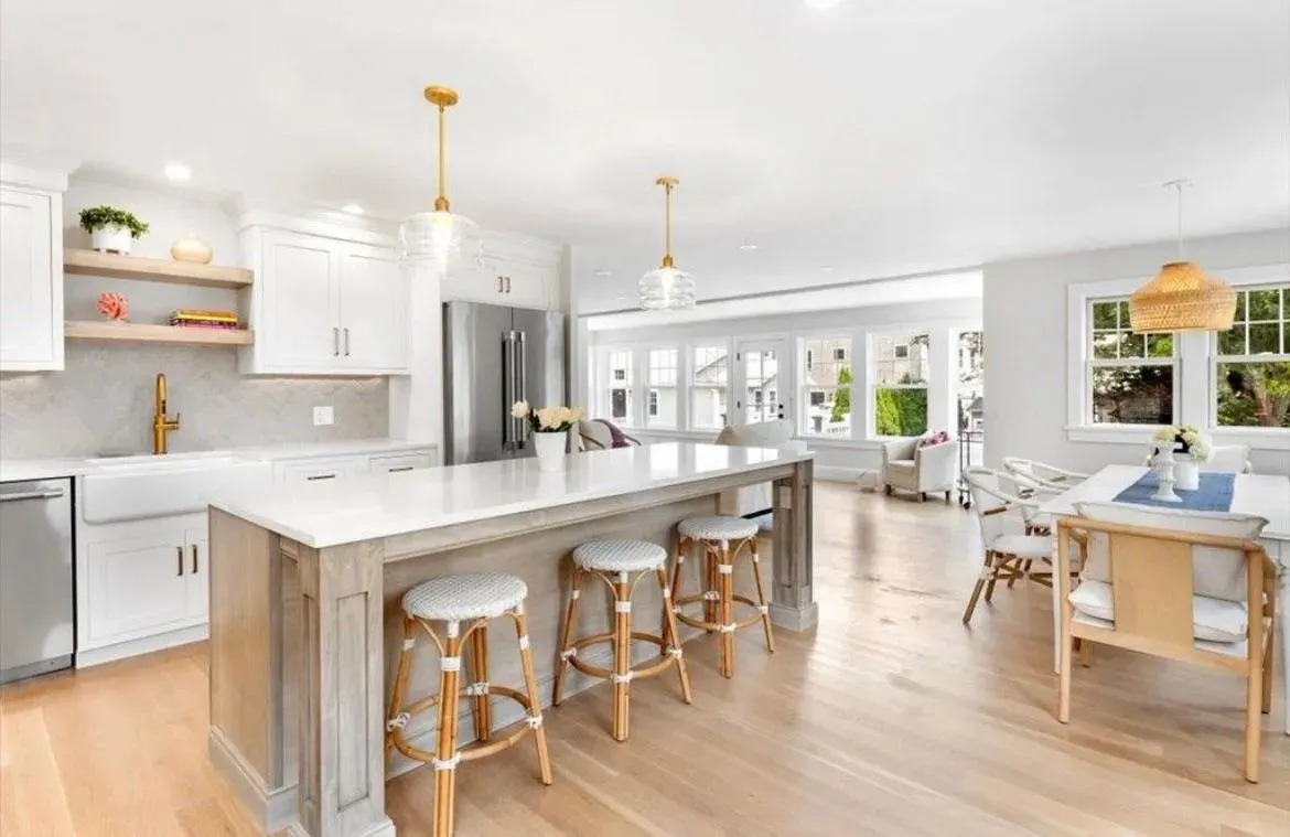 A kitchen with a large island, stools and a table.