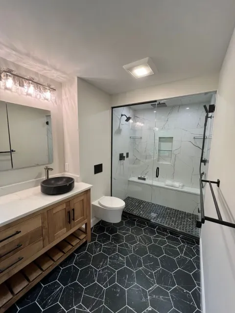 a remodeled bathroom that has gorgeous recessed lighting installed in the shower and a newly installed bathroom ventilation