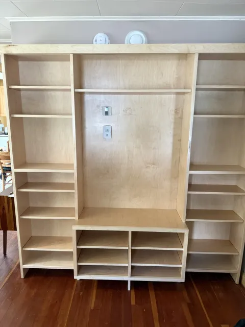 Floor-to-ceiling maple built-in with open shelving on both sides, a center TV niche and cubby storage below, finished clear