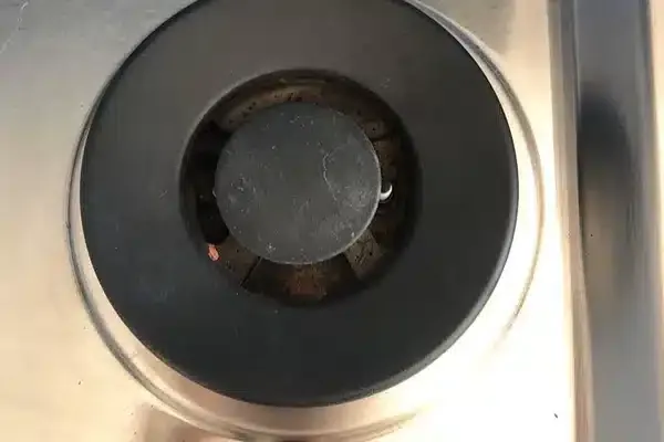 Close-up of a single gas stove burner with a black cover.