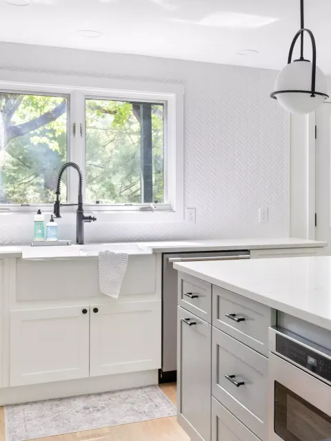 Bright kitchen featuring a farmhouse sink, herringbone wall, and modern cabinetry.