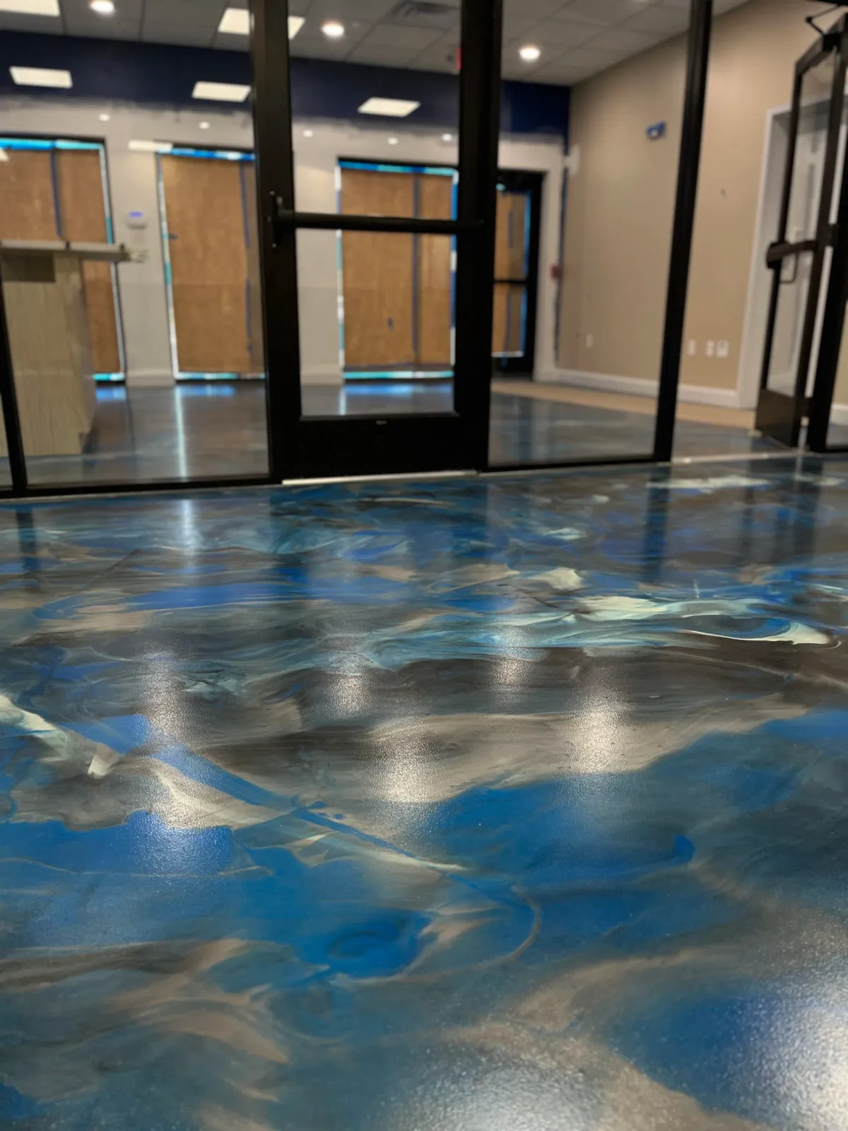 The picture depicts a low-angle shot of an epoxy floor featuring a marble swirling pattern of blue, black and white.
