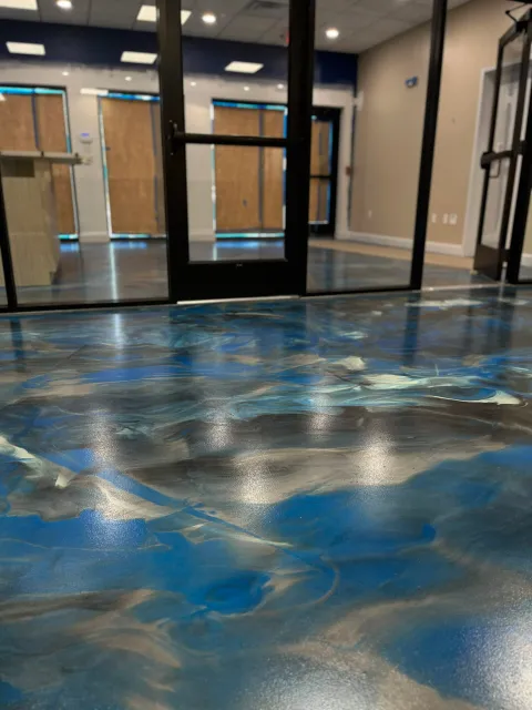 The picture depicts a low-angle shot of an epoxy floor featuring a marble swirling pattern of blue, black and white.