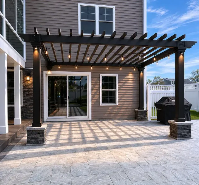 Back patio with dark wood pergola, sliding glass doors, and brick paver flooring at dusk