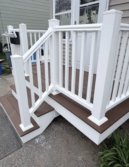 White porch ramp with railings and steps beside a house entrance