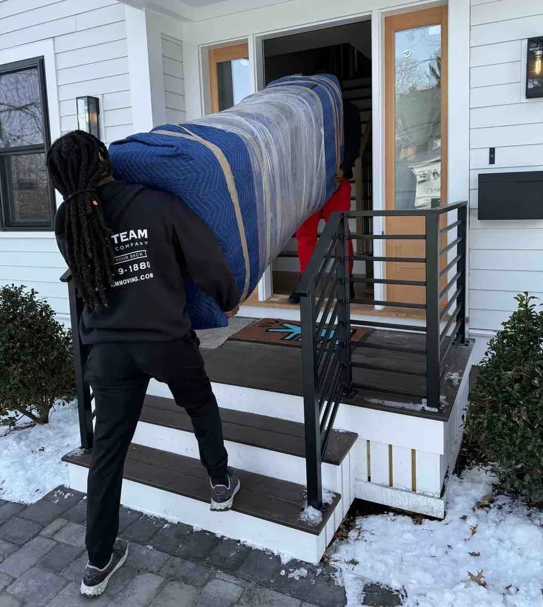 Crew in branded sweatshirts carrying a blanket-wrapped sofa