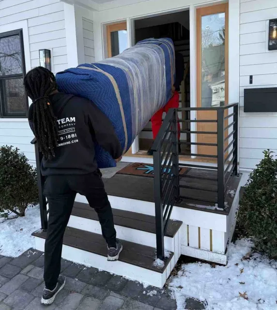Crew in branded sweatshirts carrying a blanket-wrapped sofa