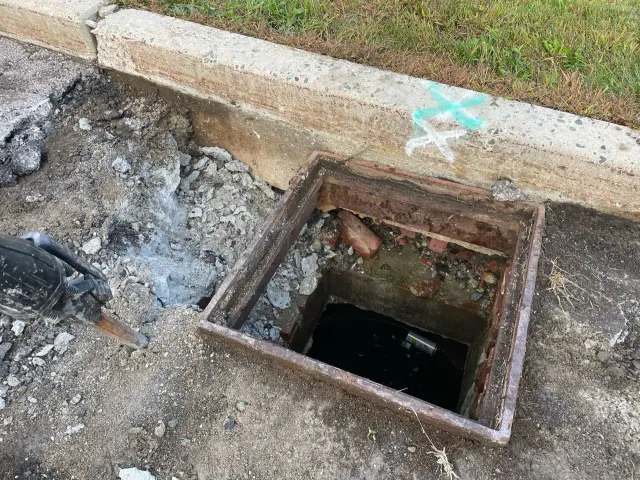A manhole cover is sitting on the ground next to a curb.