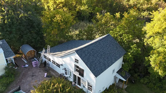 Completed charcoal shingle replacement on white Vermont farmhouse in Williston — golden hour aerial view