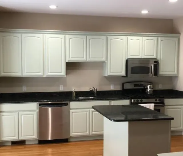 Oak kitchen cabinets refinished in a soft cream — after
