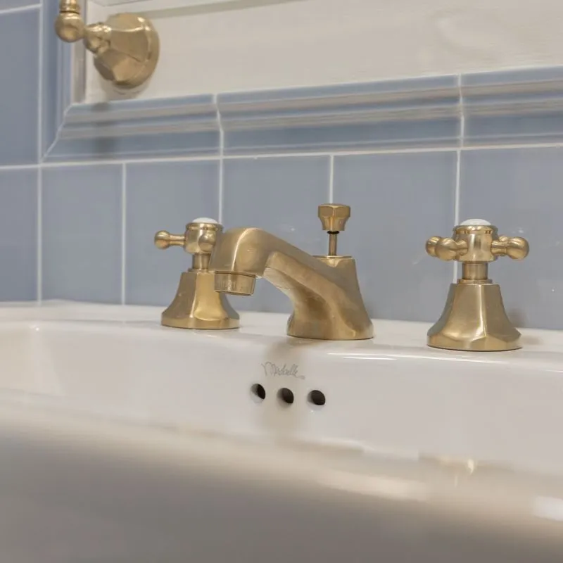 Bathroom renovation detail — brass widespread faucet on blue tile